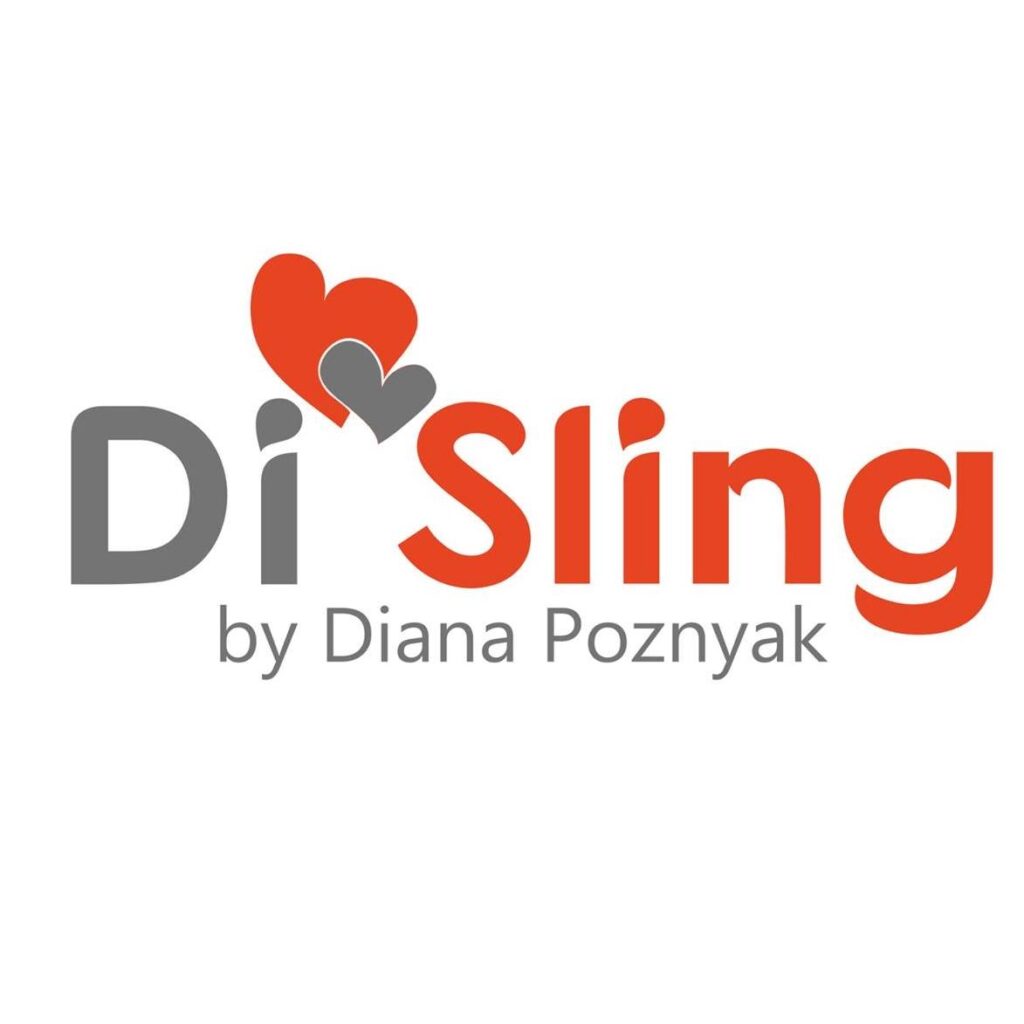 A imagem apresenta um sling de argolas em tons de azul e cinza, confeccionado em tecido leve e respirável. O padrão é discreto, com pequenas formas geométricas. O adulto usa o sling com o bebé posicionado de forma segura e confortável ao lado do corpo, permitindo liberdade de movimento. É uma opção prática para passeios diários.