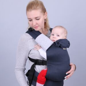 A imagem mostra uma mochila ergonómica em tons de azul escuro, feita de um tecido macio e respirável. O bebé está posicionado de forma segura e confortável, virado para o adulto, enquanto este ajusta as alças acolchoadas para um suporte adequado. O design inclui fechos práticos que facilitam o uso.